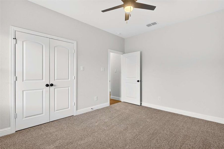 Unfurnished bedroom featuring carpet, a closet, and a ceiling fan