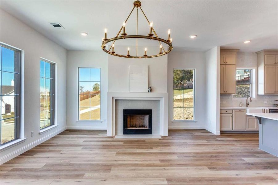 Unfurnished living room featuring light wood-style floors, a chandelier, recessed lighting, and a fireplace with flush hearth