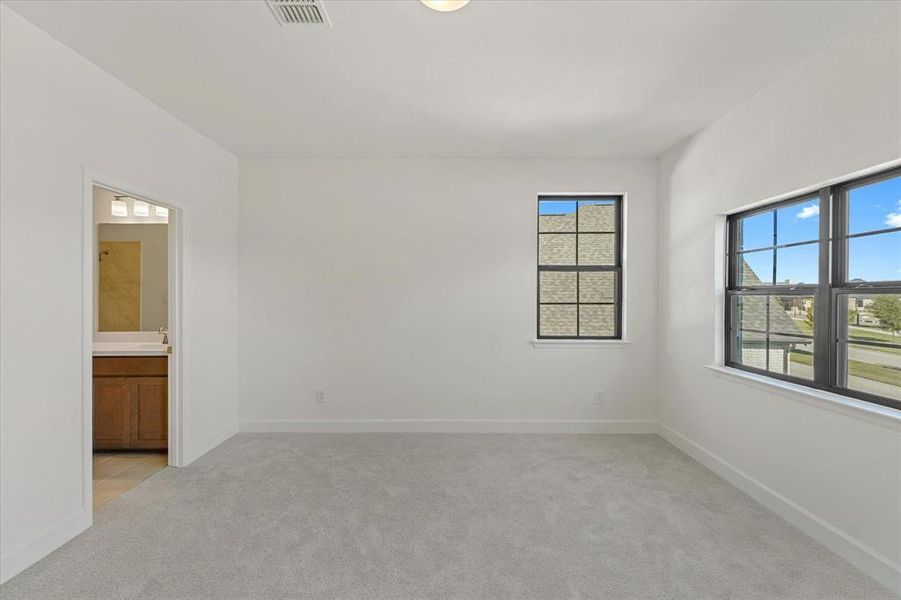 Unfurnished bedroom featuring light colored carpet and connected bathroom