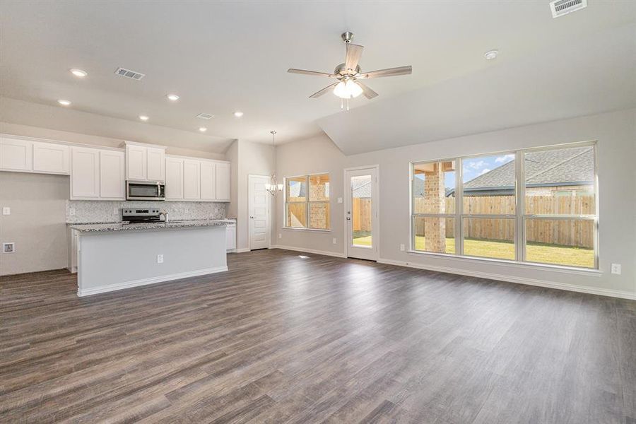 Kitchen featuring light stone countertops, appliances with stainless steel finishes, dark hardwood / wood-style flooring, white cabinetry, and an island with sink