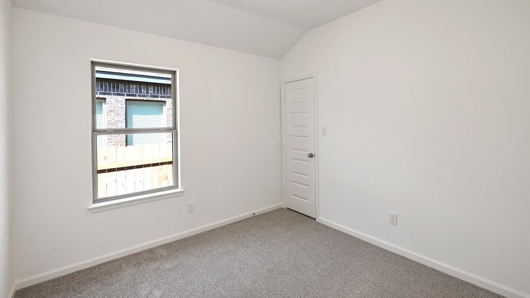 Carpeted empty room with baseboards and lofted ceiling Carpeted empty room with baseboards and lofted ceiling