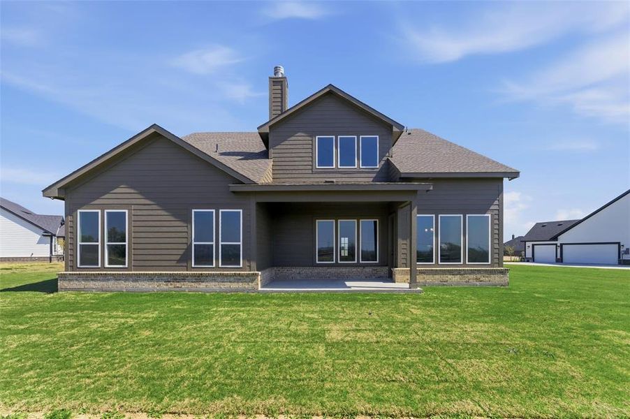 Back of house featuring a patio, roof with shingles, a chimney, brick siding, and a yard Back of house featuring a patio, roof with shingles, a chimney, brick siding, and a yard