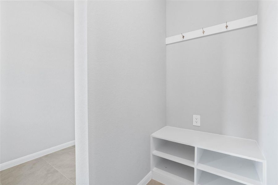 This dedicated area features a custom built-in bench with hooks, perfect for organizing coats, bags, and shoes right off the main hallway, keeping the rest of the home tidy.