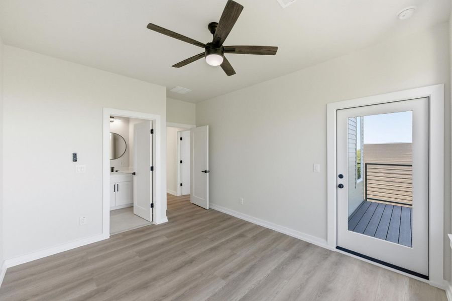 Unfurnished bedroom with light wood-style floors, access to exterior, a ceiling fan, and connected bathroom