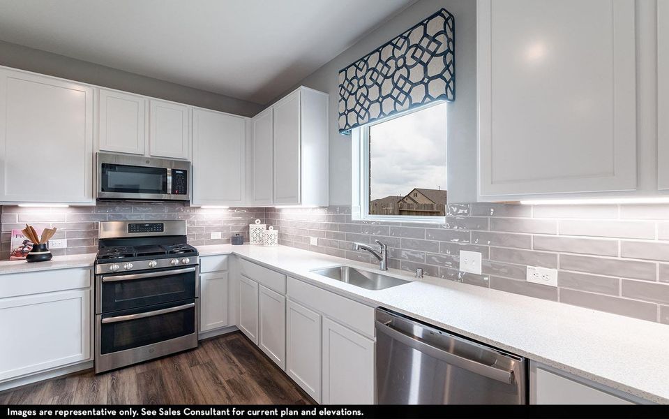 Kitchen featuring stainless steel appliances, white cabinetry, and light stone counters