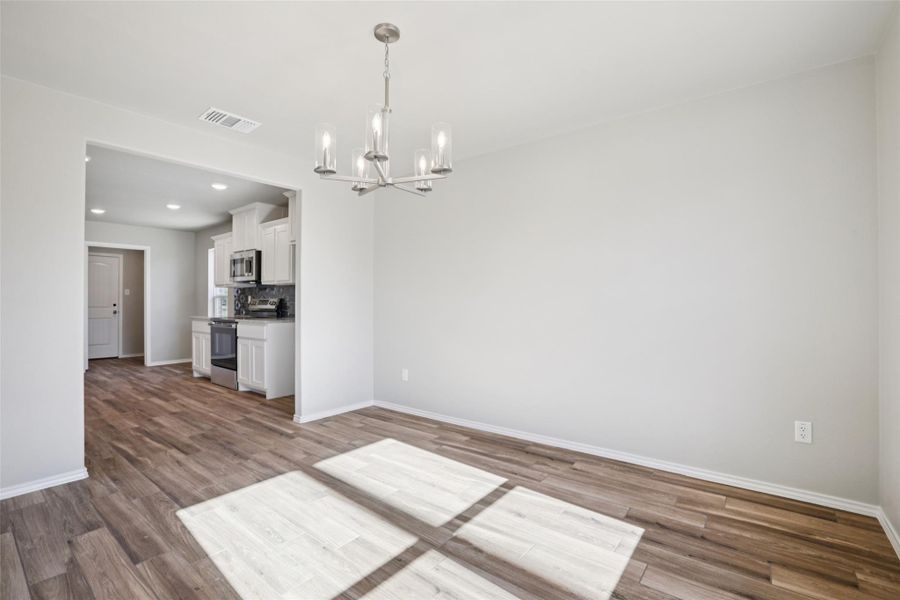 Unfurnished dining area featuring a chandelier and dark wood finished floors