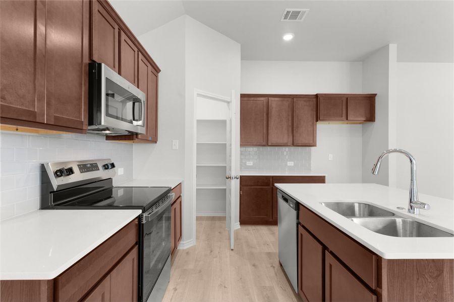 Kitchen with appliances with stainless steel finishes, light wood-style flooring, tasteful backsplash, light countertops, and recessed lighting Kitchen with appliances with stainless steel finishes, light wood-style flooring, tasteful backsplash, light countertops, and recessed lighting