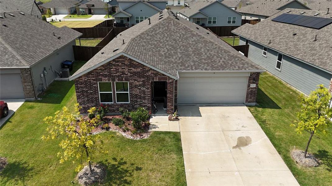 View of front facade featuring roof with shingles, brick siding, a garage, driveway, and a front lawn