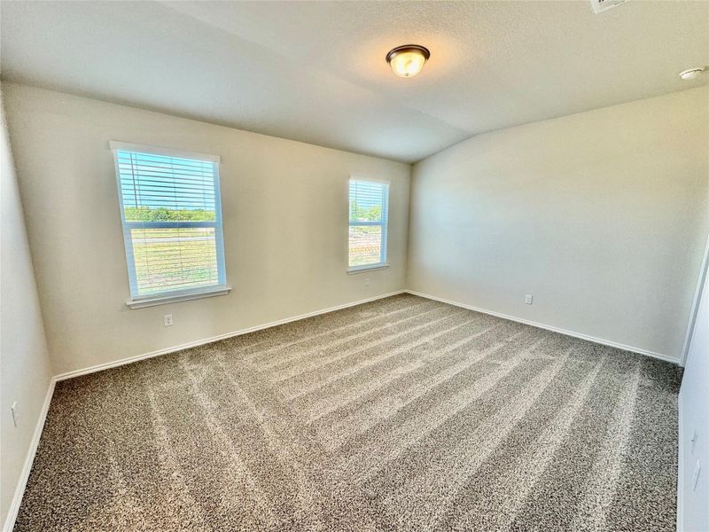 Carpeted spare room with vaulted ceiling and baseboards Carpeted spare room with vaulted ceiling and baseboards