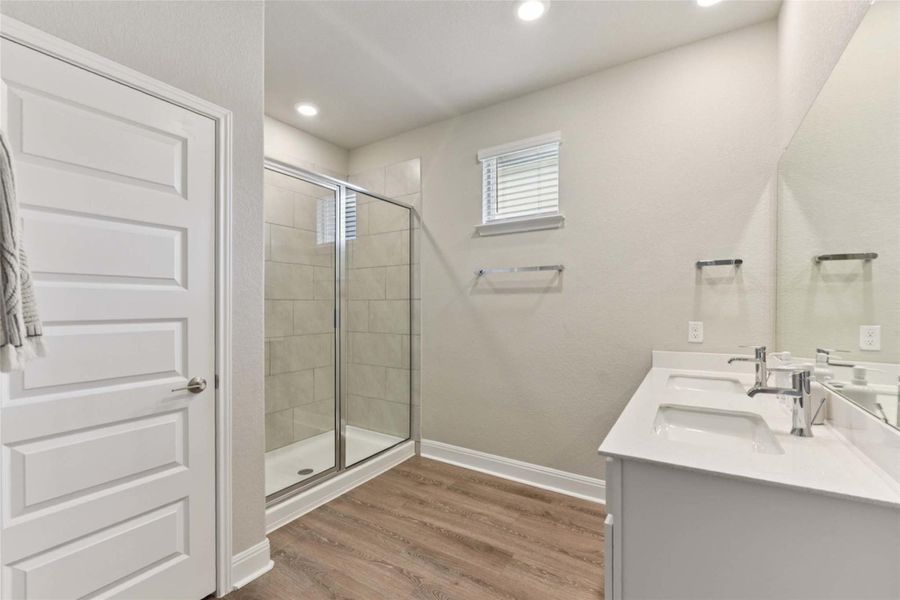 Full bathroom with wood finished floors, double vanity, a stall shower, and recessed lighting Full bathroom with wood finished floors, double vanity, a stall shower, and recessed lighting
