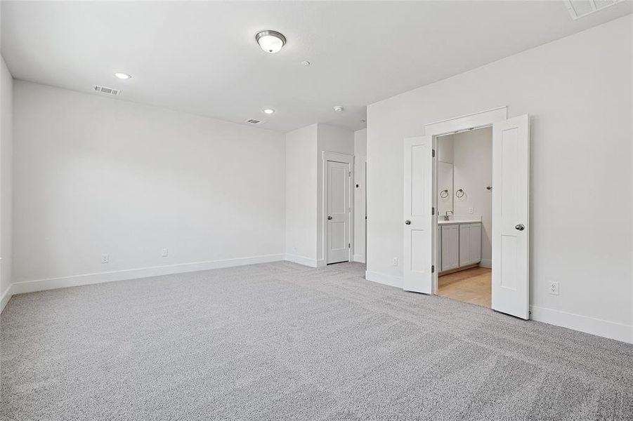 Unfurnished bedroom featuring light carpet, ensuite bath, and recessed lighting