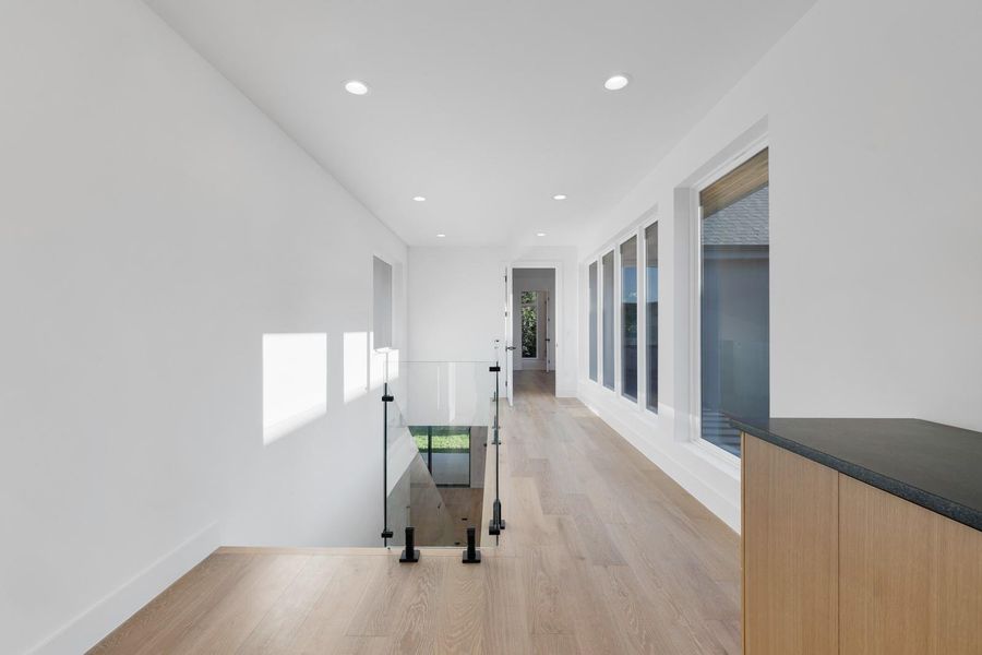 Hallway with light wood-style floors, recessed lighting, and an upstairs landing