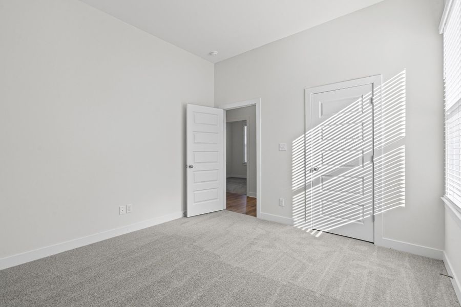 Unfurnished bedroom with light colored carpet and baseboards