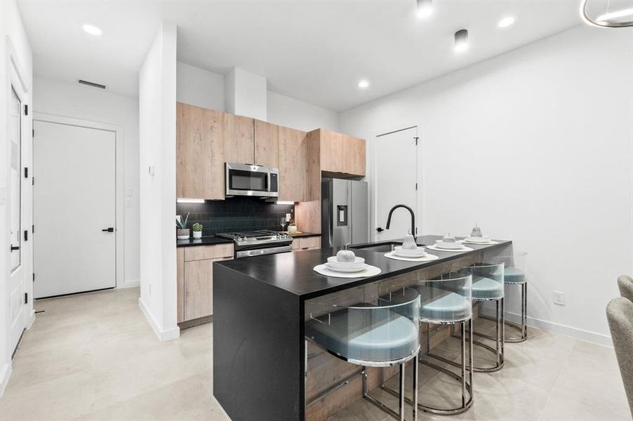 Quartz countertops, edge pull cabinetry, and stainless steel appliances throughout the kitchen