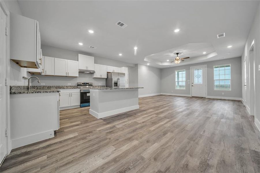 Kitchen featuring a kitchen island, white cabinetry, ceiling fan, stainless steel appliances, and light hardwood / wood-style flooring