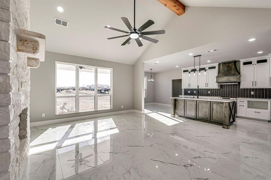 Kitchen with custom range hood, ceiling fan with notable chandelier, visible vents, and marble finish floor