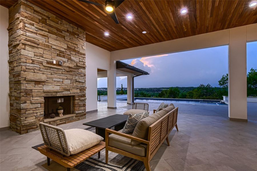 Outdoor living area featuring a stone fireplace, a wood plank ceiling with recessed lighting, and a ceiling fan