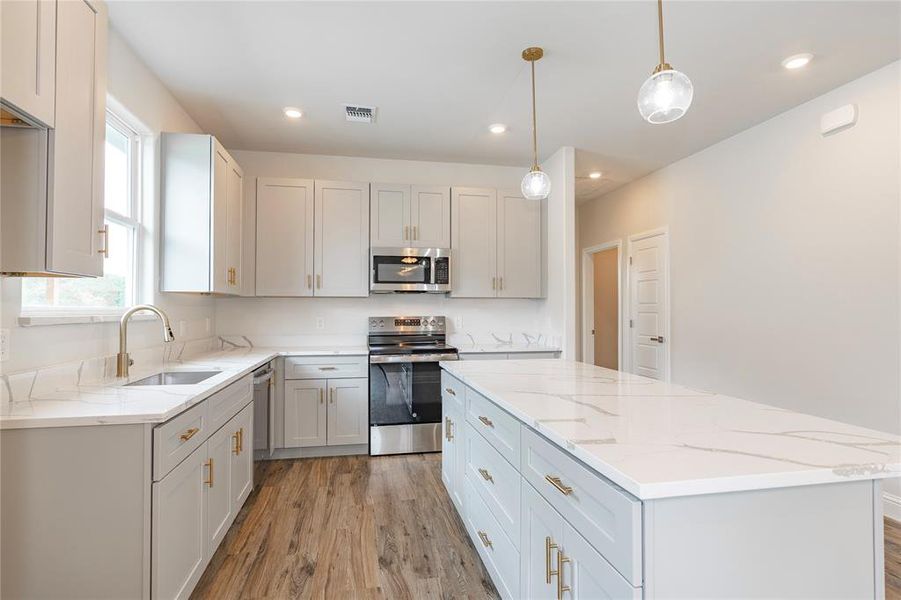 Kitchen featuring a center island, decorative light fixtures, light wood-type flooring, stainless steel appliances, and sink