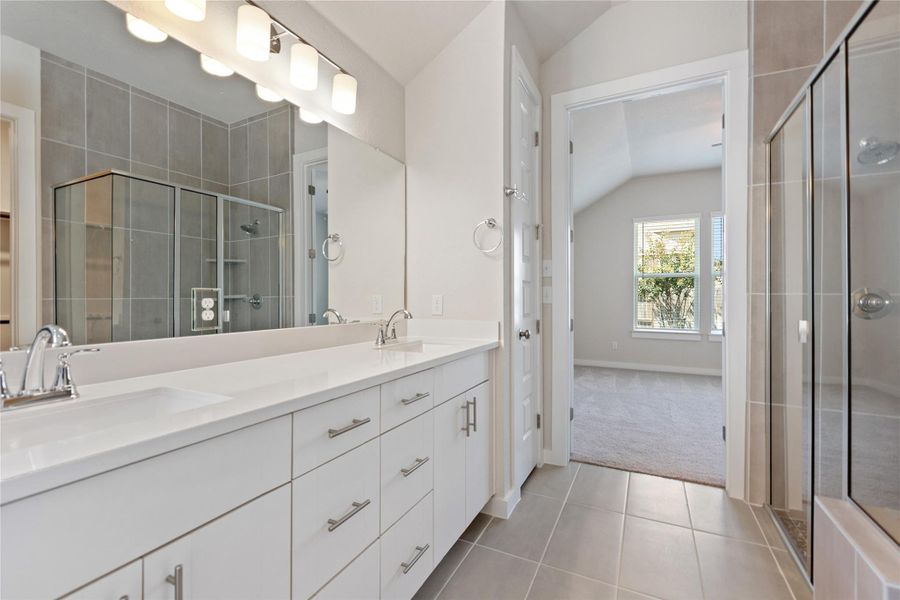 Full bathroom featuring light tile patterned floors, lofted ceiling, double vanity, a shower stall, and light colored carpet