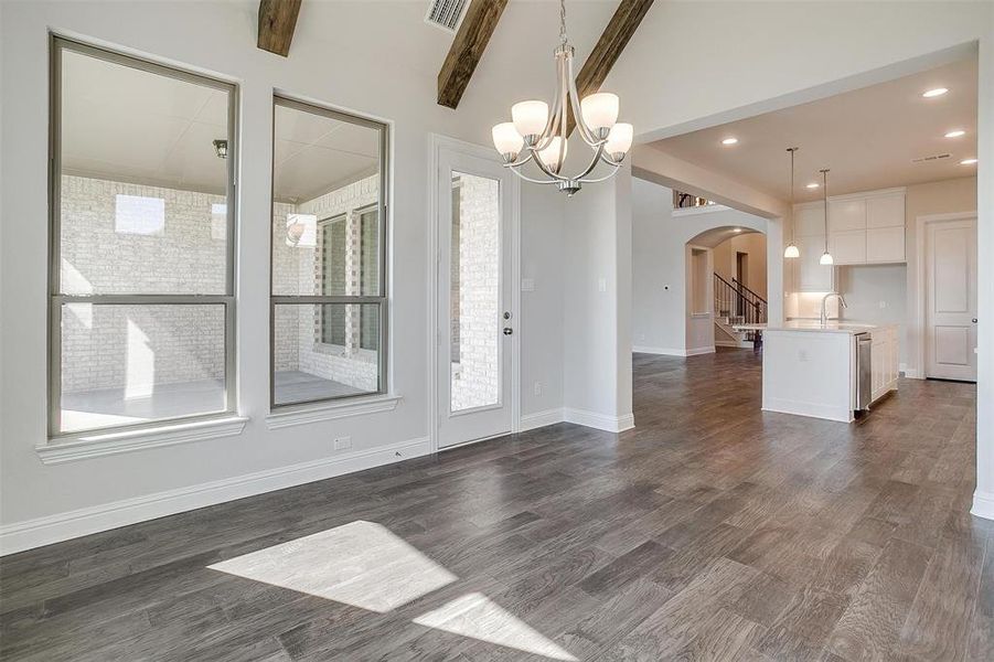 Unfurnished dining area with a notable chandelier, sink, dark hardwood / wood-style floors, and beam ceiling