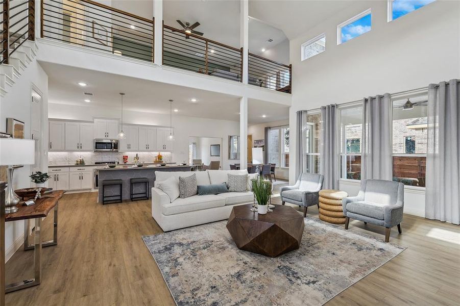 Open-concept living space featuring high ceilings with upper-level windows, wood-finish flooring, and white walls