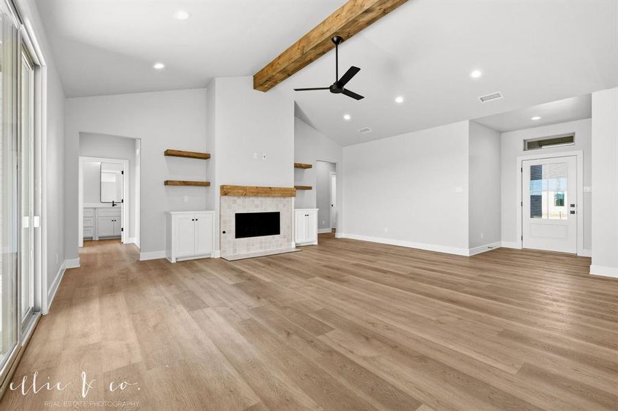 Unfurnished living room featuring beam ceiling, a fireplace, a ceiling fan, light wood-style flooring, and recessed lighting