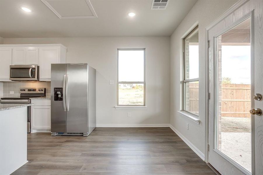 Kitchen with appliances with stainless steel finishes, white cabinetry, decorative backsplash, recessed lighting, and dark wood-type flooring