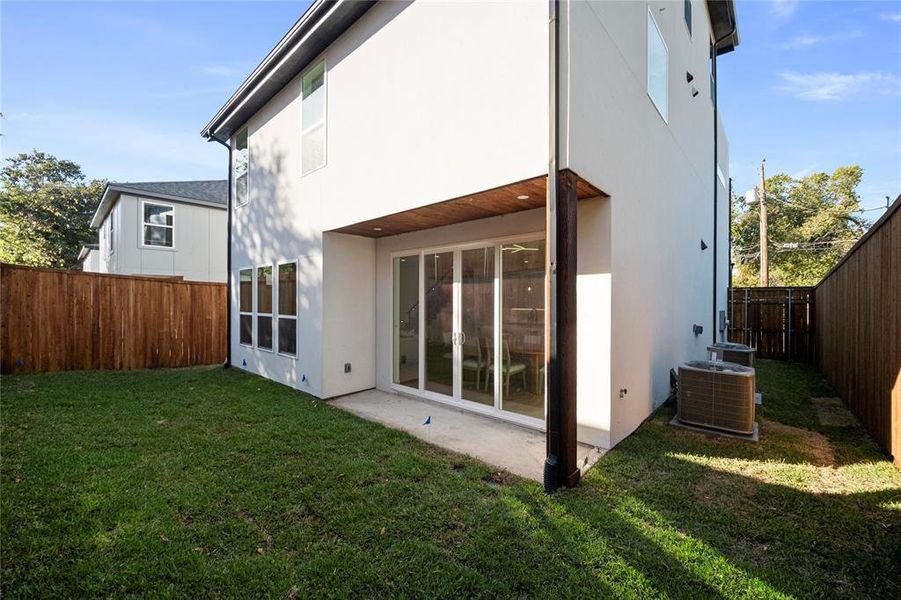 Rear view of property featuring central air condition unit and a lawn