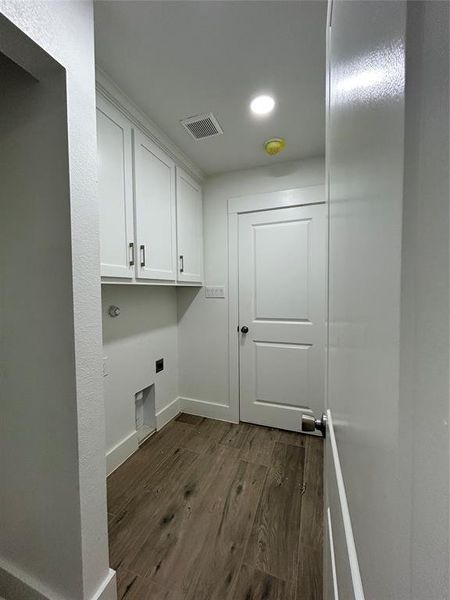 Laundry area with cabinets, hookup for an electric dryer, and dark hardwood / wood-style floors