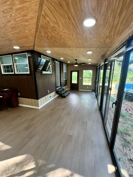 A generous sunroom with full-length windows overlooks the natural surroundings, extending the living space outdoors.