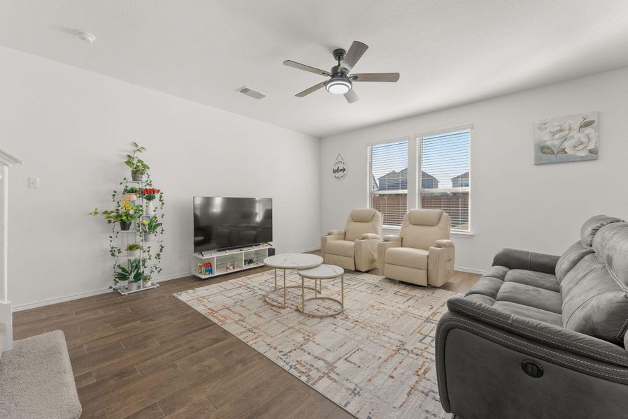 Living room with a ceiling fan, visible vents, baseboards, and wood finished floors