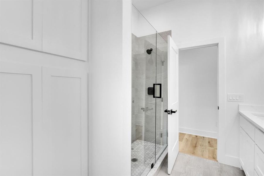 Bathroom with a shower with shower door, vanity, and hardwood / wood-style floors