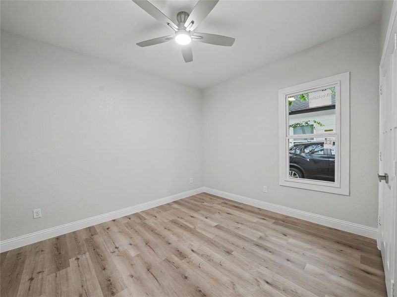Room featuring wood-finish flooring, white baseboards, and a single window with white trim