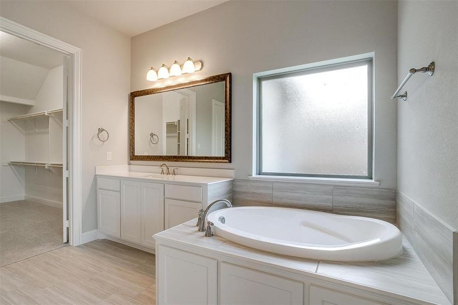 Bathroom with vanity, a wealth of natural light, and a relaxing tiled tub