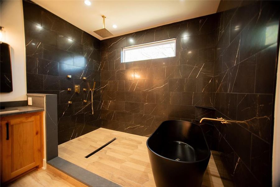 Full bathroom with tile walls, a soaking tub, recessed lighting, vanity, and a walk in shower Full bathroom with tile walls, a soaking tub, recessed lighting, vanity, and a walk in shower