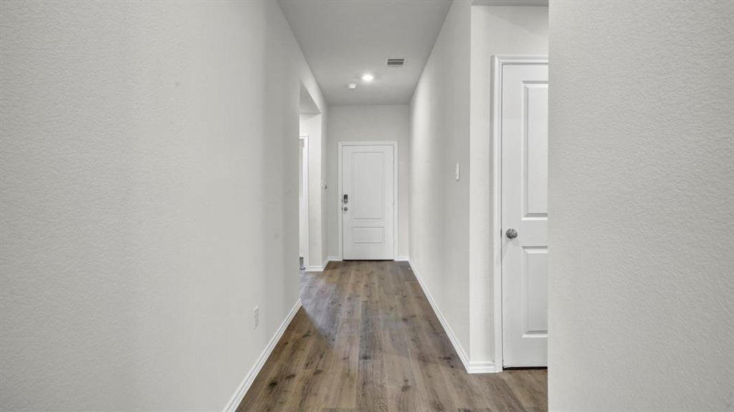 Hallway featuring wood-finish flooring, white baseboards, recessed lighting, and a white paneled door