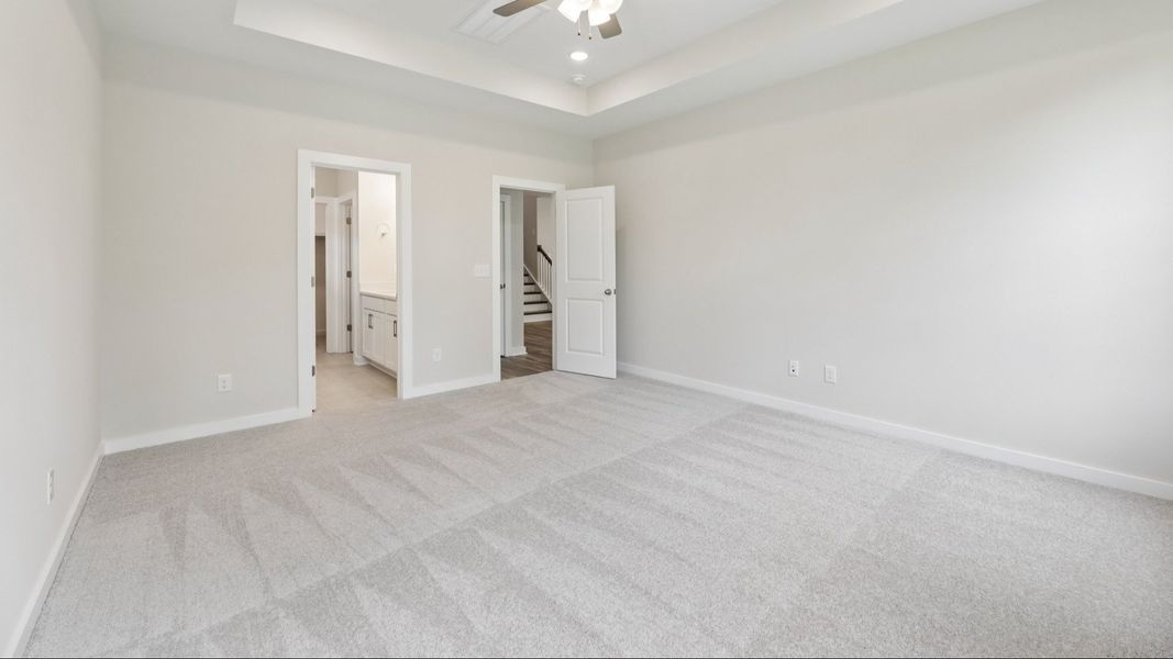Primary Bedroom with tray ceiling and carpet