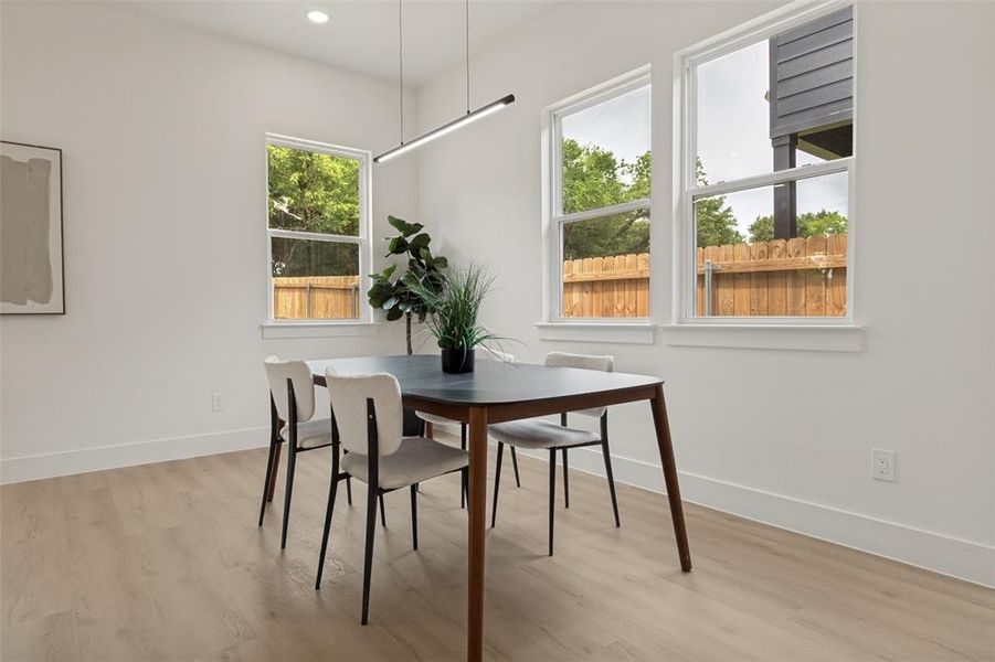 Dining area featuring white walls, wood-finish flooring, and multiple windows