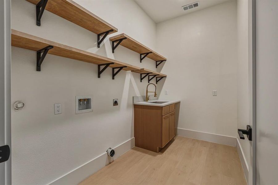 Laundry room featuring light wood-type flooring, cabinet space, washer hookup, and electric dryer hookup