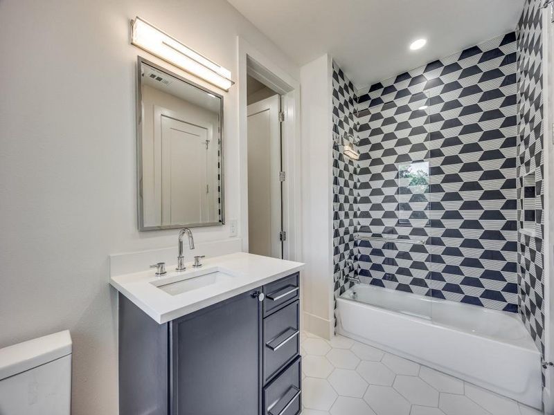 Full bathroom featuring tile patterned flooring, vanity, toilet, and tiled shower / bath combo