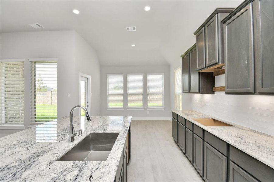 Culinary haven, featuring granite countertops, a tile backsplash, stainless steel appliances (to be installed), and 42” upper cabinets.