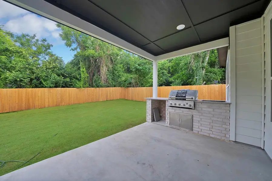 Covered patio featuring an outdoor kitchen with an integrated grill, brick base, and stainless steel cabinetry Covered patio featuring an outdoor kitchen with an integrated grill, brick base, and stainless steel cabinetry