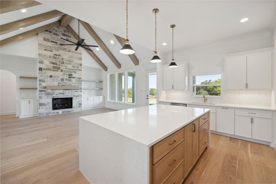 Kitchen featuring a center island, light wood-type flooring, white cabinetry, lofted ceiling with beams, and decorative light fixtures