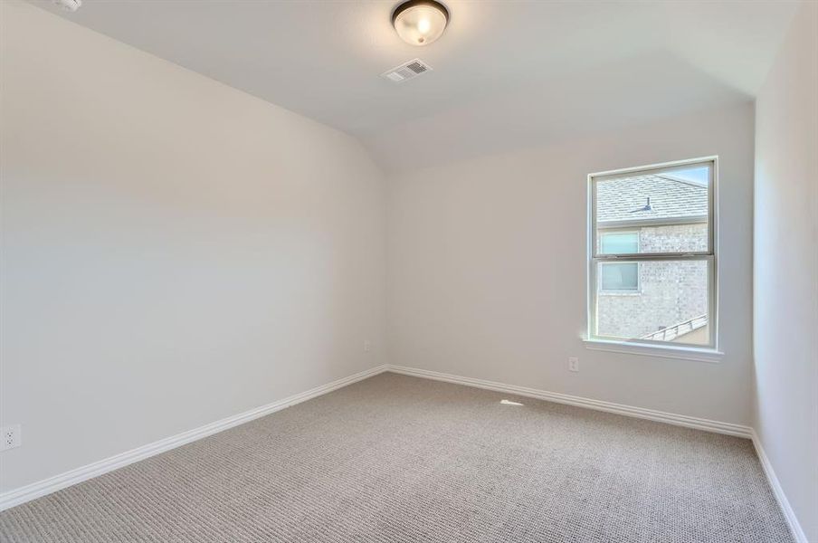 Unfurnished room with vaulted ceiling and carpet flooring