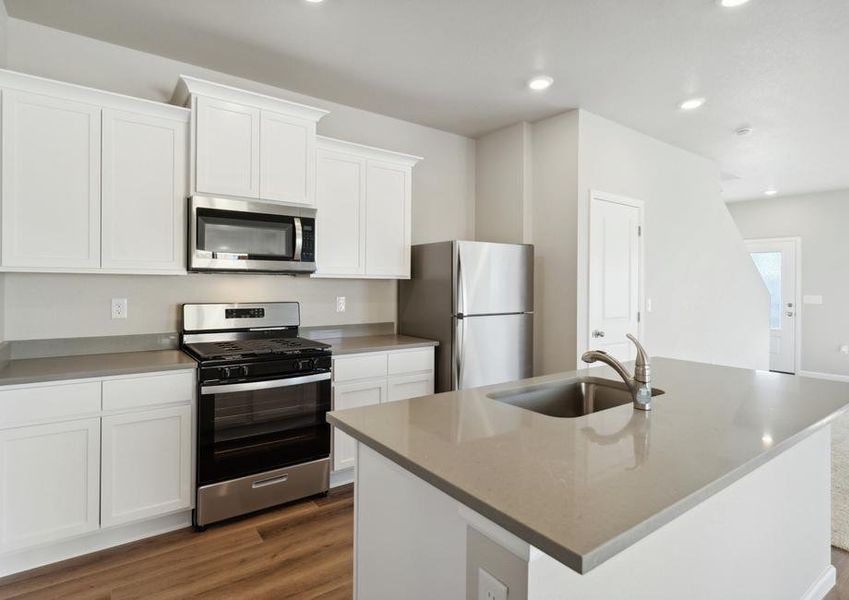 The kitchen has stainless steel appliances and plank flooring.