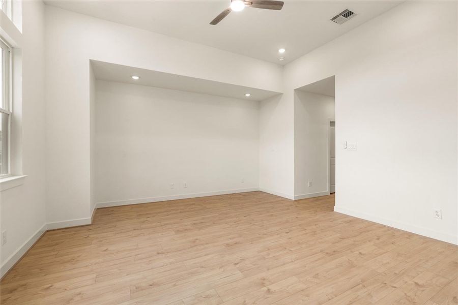Expansive primary bedroom layout — clean neutral walls, recessed lighting, ceiling fan detail, and direct access to the ensuite bath.