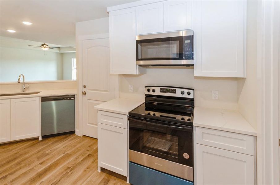 Kitchen featuring appliances with stainless steel finishes, sink, light hardwood / wood-style flooring, and white cabinets