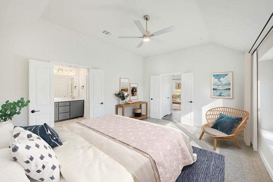 Master bedroom with vaulted ceiling, ceiling fan, carpet flooring, and ensuite bathroom visible through open door
