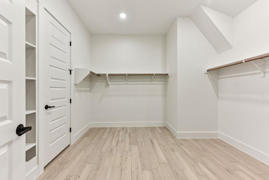 Walk in closet with light wood-style floors