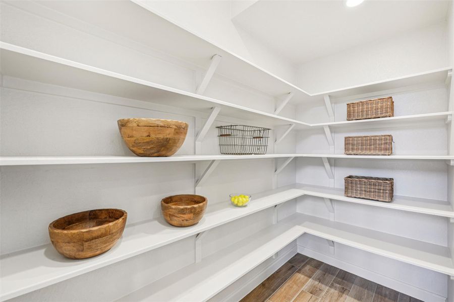 The pantry features extensive white shelving, a light-colored floor, and recessed lighting